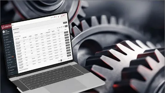 A laptop showing structured records beside industrial cogs